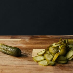 Sliced pickles on a wooden board with rustic background, highlighting freshness and simplicity.